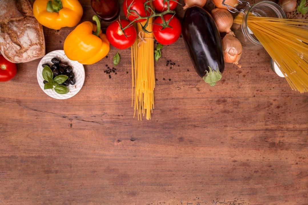 Legumes frescos, pão, massa e azeite sobre uma mesa de madeira